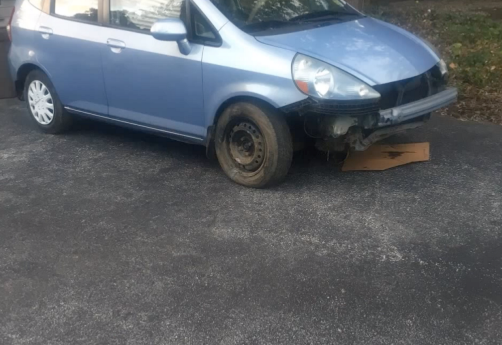 a blue honda fit (compact car) without the bumper.